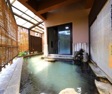 Sheltered onsen with bamboo screens and stone edging at a ryokan in Saga, Kyushu