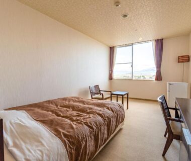 Western-style room with single bed, desk, chairs and window at Ooedo Onsen Monogatari Aizu, Fukushima
