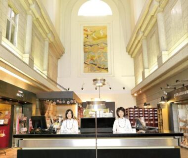 Lobby front desk with staff under tall arched ceiling and storefronts at Ooedo Onsen Monogatari Aizu, Fukushima