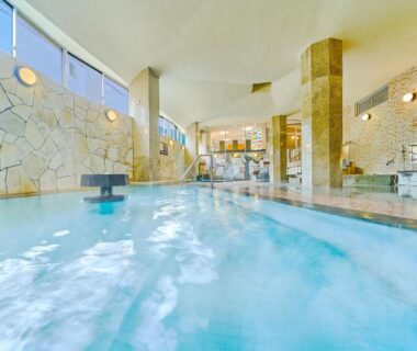 Large indoor onsen pool with stone wall and windows at Ooedo Onsen Monogatari Gero Bekkan Gifu