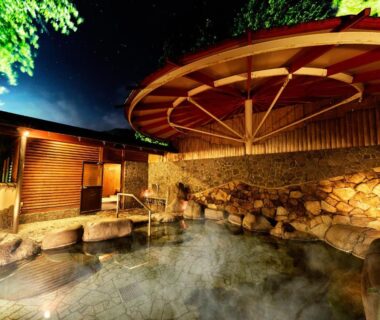 Steaming outdoor onsen with wooden shelter and stone edging at Ooedo Onsen Monogatari Gero Bekkan in Gifu, Japan