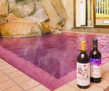 Indoor purple onsen bath with two wine bottles at edge Ooedo Onsen Monogatari Hotel Shinko Yamanashi