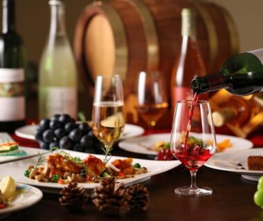 Table set with wine being poured, glasses and assorted dishes with grapes at Ooedo Onsen Monogatari Hotel Shinko Yamanashi