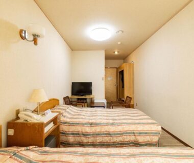 Narrow twin bedroom with two beds, TV and bedside table at Ooedo Onsen Monogatari Kounkaku in Miyagi Tohoku