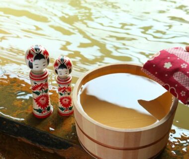Wooden onsen bucket and two kokeshi dolls by hot spring water at Ooedo Onsen Monogatari Kounkaku, Miyagi