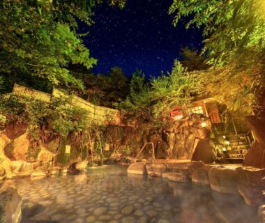 Night outdoor stone onsen with lanterns and trees at Ooedo Onsen Monogatari Miyoshiya, Hyōgo