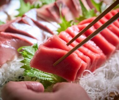 Chopsticks picking fresh tuna sashimi on shredded daikon with shiso at Ooedo Onsen Monogatari Miyoshiya Hyōgo