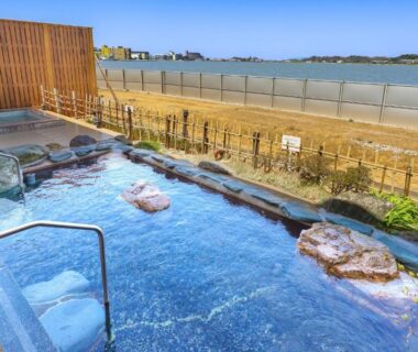 Outdoor onsen bath with rock features overlooking coastal waters at Ooedo Onsen Monogatari Nagayama, Ishikawa