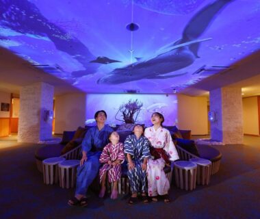 Family wearing yukata seated under illuminated ceiling art at Ooedo Onsen Monogatari Premium Atami, Shizuoka Chūbu