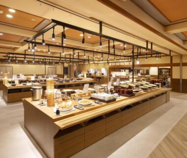 Spacious buffet dining hall with warm wooden interior and food stations at Ooedo Onsen Monogatari Premium Kaga Maruya, Ishikawa