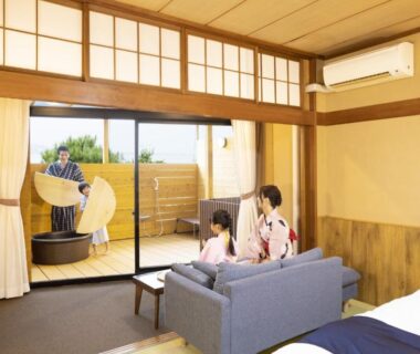 Guests in yukata in tatami room with sofa and wooden balcony bath at Ooedo Onsen Monogatari Kaga Maruya Ishikawa
