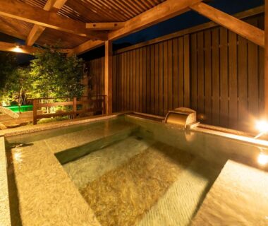 Covered stone onsen bath with wooden beams and warm lantern lighting at Ooedo Onsen Monogatari Premium Kinosaki, Hyōgo