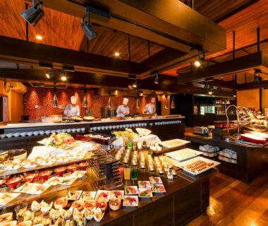 Assorted buffet dishes and chefs in a warm wooden dining hall at Ooedo Kinosaki, Hyōgo