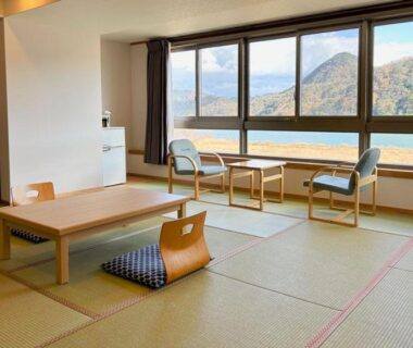 Spacious tatami room with low table, zabuton cushion, window seating and mountain view at Ooedo Onsen Monogatari Kinosaki Hyōgo