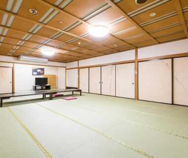 Spacious tatami room with low tables, seating cushions and sliding doors at a Kinosaki ryokan in Hyōgo