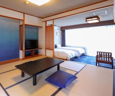 Tatami seating area with low table and western beds in ryokan room at Ooedo Onsen Monogatari, Tochigi