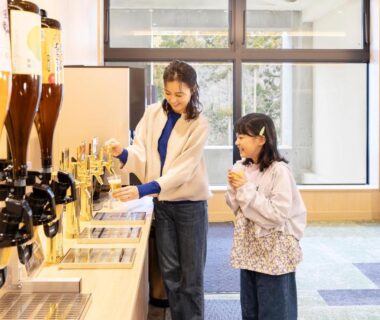 Woman and child using self-serve beverage dispensers in hotel dining area at Ooedo Onsen Monogatari Yamanaka Grand Hotel Ishikawa