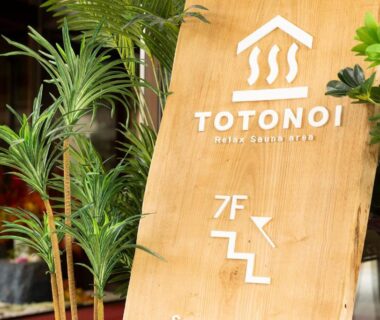 Wooden Totonoi signboard with logo and potted plants indicating entrance at Ooedo Onsen Monogatari, Ishikawa