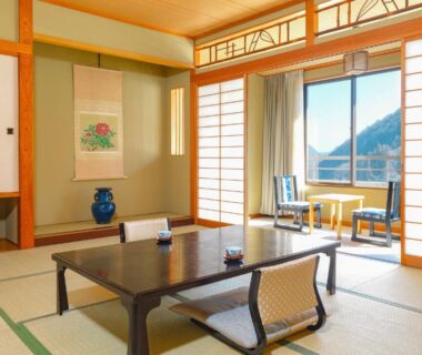 Tatami room with low table, shoji screens and mountain view at Ooedo Onsen Monogatari Shinshu Kakeyu, Nagano, Chūbu, Japan