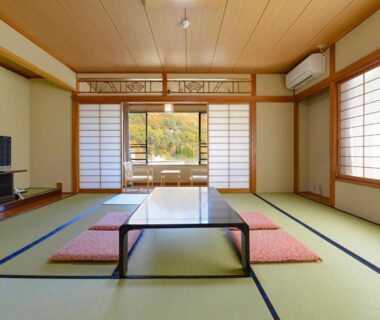 Traditional tatami room with low table, cushions, shoji screens and garden view at Ooedo Onsen Monogatari Shinshu Kakeyu, Nagano