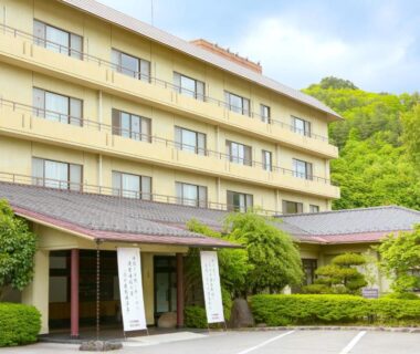 Front entrance and facade of Ooedo Onsen Monogatari Shinshu Kakeyu with surrounding greenery in Nagano