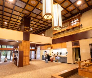 Wooden-ceiling ryokan lobby with reception desk and seating area at Ooedo Onsen Monogatari Yamashiro Saichoraku Ishikawa