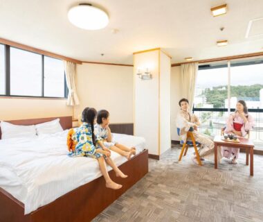 Family relaxing in Western-style room with beds and balcony at Ooedo Onsen Monogatari Yamashiro Saichoraku Ishikawa