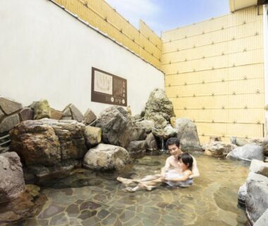 Couple relaxing in stone outdoor onsen at Ooedo Onsen Monogatari Yamashiro Saichoraku, Chūbu Ishikawa