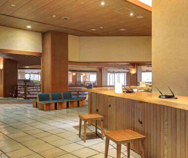 Spacious ryokan reception area with wooden counter, stools, tiled floor and lounge seating at Ookawaso in Fukushima