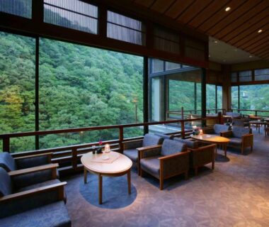 Lounge with sofas and tables overlooking forested mountains at Ookawaso in Fukushima