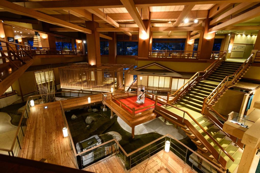 Warm wooden ryokan lobby at Ookawaso Fukushima Grand wooden lobby with indoor water feature, staircases, shoji screens and warm lighting at Ookawaso, Tōhoku