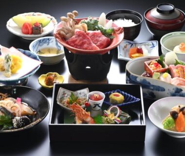Assorted multi-course Japanese dinner on lacquer trays and small bowls with grilled fish and simmered vegetables