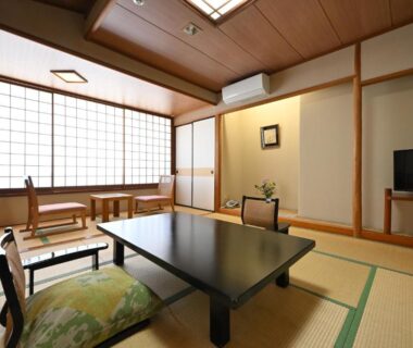 Traditional tatami room with low table, zabuton chairs, shoji screens and tokonoma at Osakaya Ryokan, Gunma