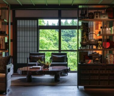 Seating area with low table, shoji screens and bookshelves at Osawakan, Niigata
