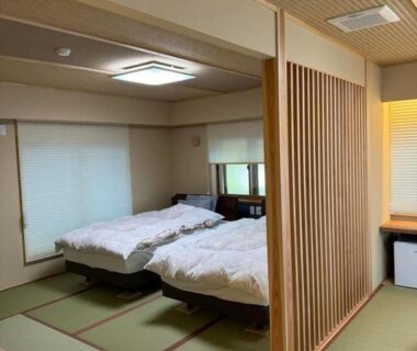 Traditional tatami flooring, twin beds, wooden room divider and shoji screens in a calm ryokan room