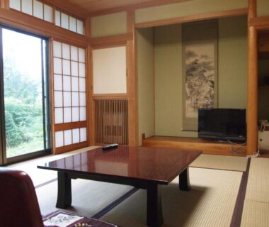 Traditional tatami room with low table, shoji screens, tokonoma alcove and garden view at Oshi Ryokan Nagano