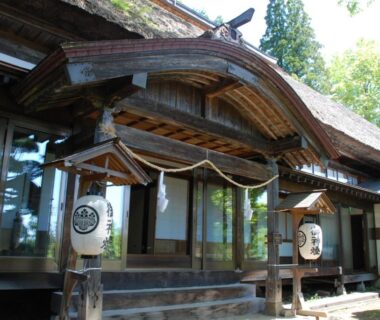 Wooden entrance with shimenawa rope and lanterns at Oshi Ryokan in Nagano, Chubu, Japan