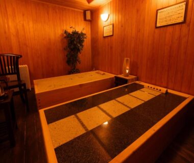 Warm wooden bathing room with two rectangular tubs and seating at Otowaya Ryokan, Niigata