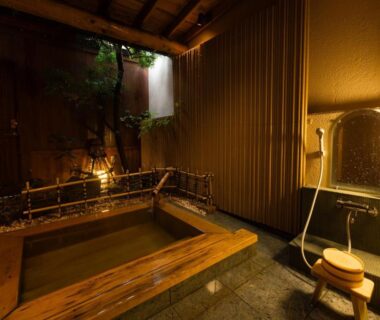 Wooden soaking tub with shower stool, bamboo screens and warm lighting at Otowaya Ryokan in Niigata