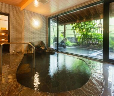 Stone indoor onsen with glass wall overlooking a garden at Otowaya Ryokan in Niigata