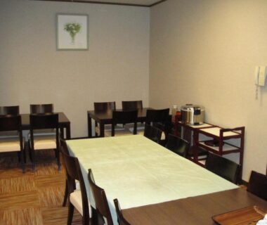 Communal dining room with rectangular table, wooden chairs and beverage station at Otowaya Ryokan Niigata Chūbu