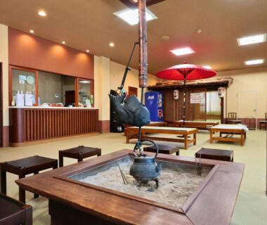 Traditional irori hearth with hanging kettle, low tables, tatami seating and red umbrella in Oyado Hachibei lobby, Gifu, Chūbu Japan