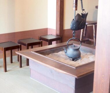 Traditional irori hearth with hanging iron kettle and wooden seating on tatami at Oyado Hachibei in Gifu