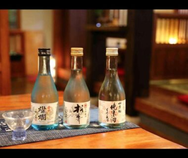 Three sake bottles and cup on wooden table in tatami interior at Oyado Ichifuji, Tochigi