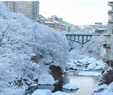 Snow-blanketed river, arched bridge and riverside buildings near Oyado Ichifuji in Tochigi