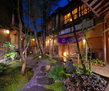 Lantern lit stone path through courtyard with pond, entrance of Oyado Ichizen, Oita, Kyushu, Japan