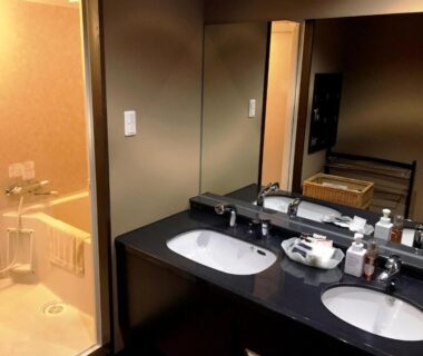 Double vanity with two sinks and mirror beside enclosed bath at Oyado Kinkiyu Annex SUIKAZURA Hokkaidō