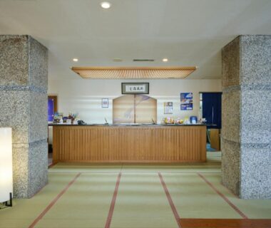 Lobby with wooden reception counter, tatami-style flooring and stone pillars at Oyado Kiyomizuya in Hokkaidō