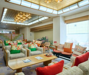 Spacious lounge with sofas, colorful cushions, low wooden tables and large windows at Oyado Kiyomizuya