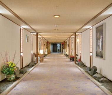 Carpeted ryokan corridor with shoji screens, floral arrangements and soft lighting at Oyado Kiyomizuya in Hokkaido